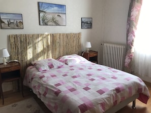 Une chambre à coucher avec un lit, une table de chevet, une lampe et deux tableaux encadrés accrochés au mur.