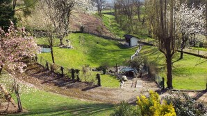 A rural landscape with a small white building, possibly a guesthouse, surrounded by lush green fields and blooming trees. - The Hydrangeas suite - quality services (in the countryside in Lourdes) (Lourdes)