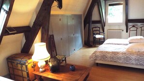 A bedroom with a bed, a desk with a lamp, a chair, and a chest of drawers. - The Hydrangeas suite - quality services (in the countryside in Lourdes) (Lourdes)