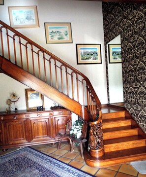 A wooden staircase with a railing, a wooden cabinet, and a patterned rug. - The Hydrangeas suite - quality services (in the countryside in Lourdes) (Lourdes)