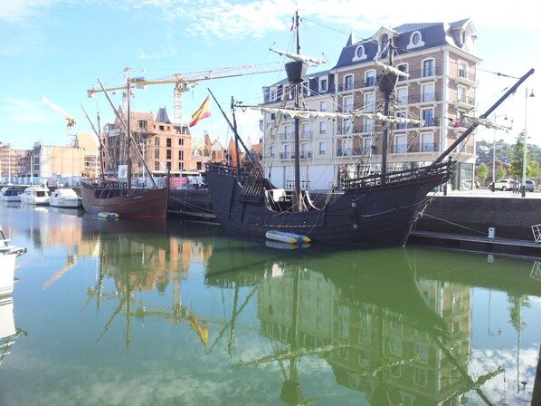 Ein historisches Schiff liegt im Hafen vor einer Gebäudereihe.