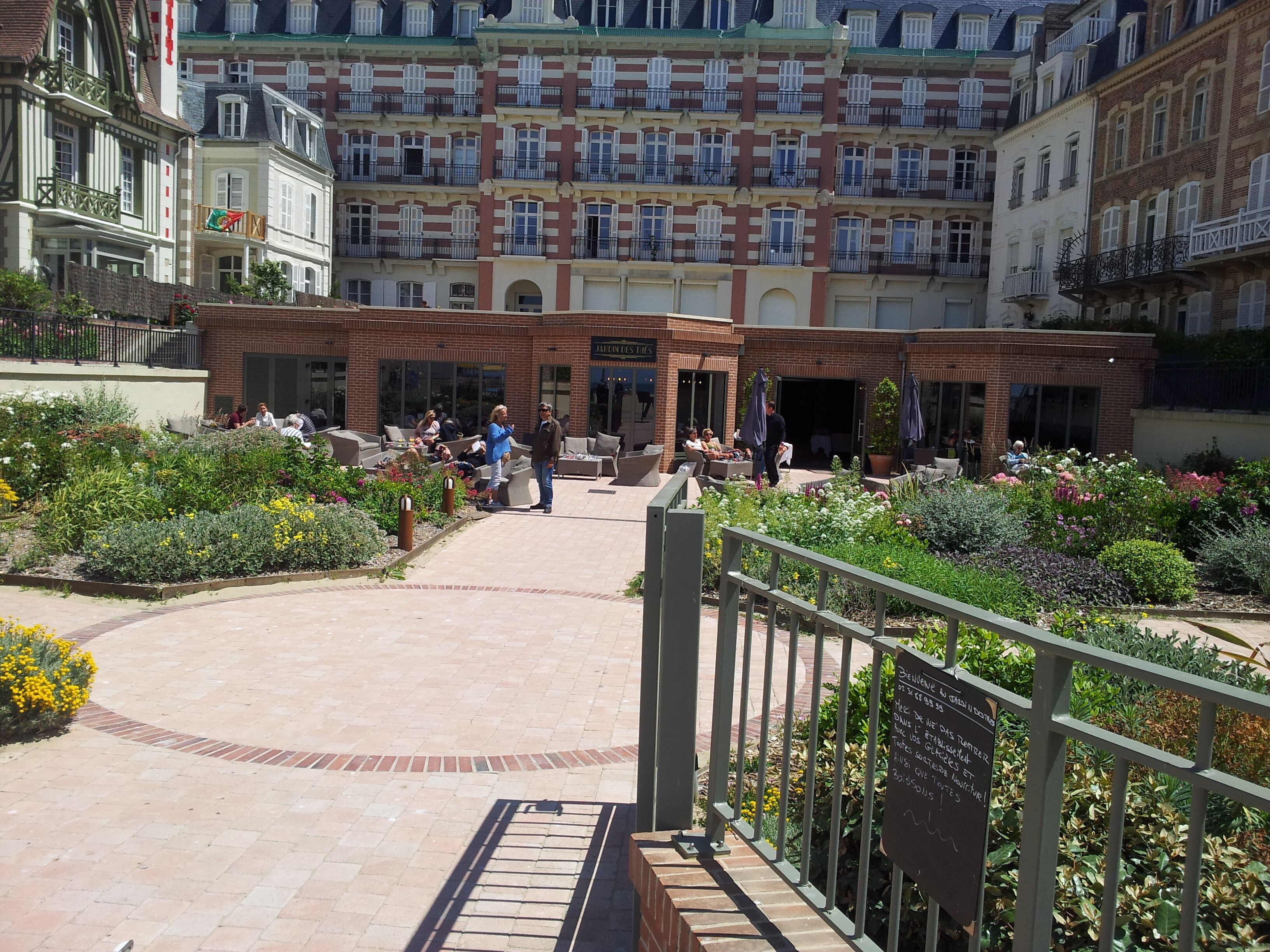 A courtyard with a brick pathway, outdoor seating, and a variety of plants.