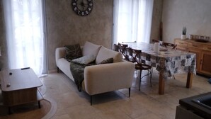 Ein Wohnzimmer mit einer Couch, einem Esstisch und einer Küchenzeile.