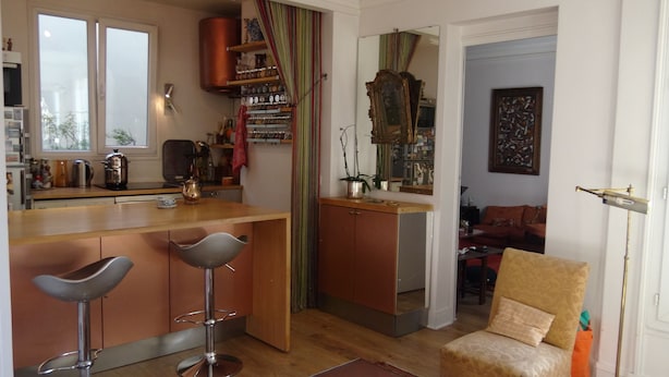 A compact living space with a kitchen area, a dining area with bar stools, a sofa, and a chair. - quiet and refined apartment (Paris)