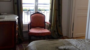 A bedroom with a bed, a chair, a desk, and a window with curtains. - quiet and refined apartment (Paris)