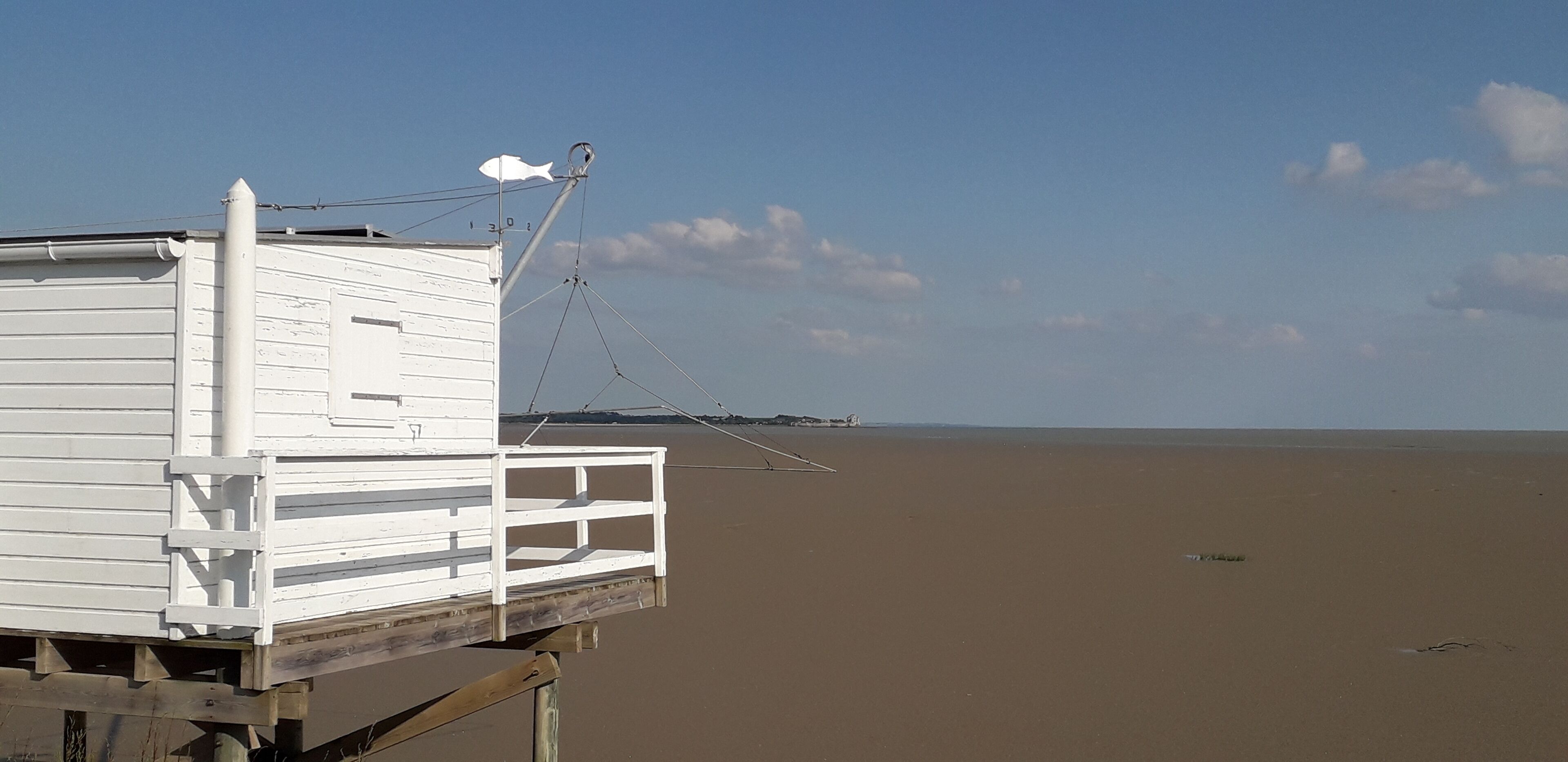 Une tour de surveillance blanche, dotée d’une rambarde, se dresse sur une plage de sable.