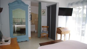 A bedroom with a bed, a mirror, a television, and a wooden table. - Seaside guest room 1 (Portbail)