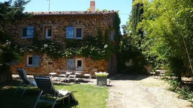 A stone building with a garden patio, outdoor seating, and a stone pathway.