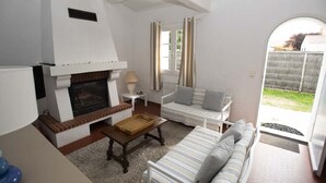 Un salon chaleureux avec une cheminée, un canapé, une petite table et une vue sur le jardin.