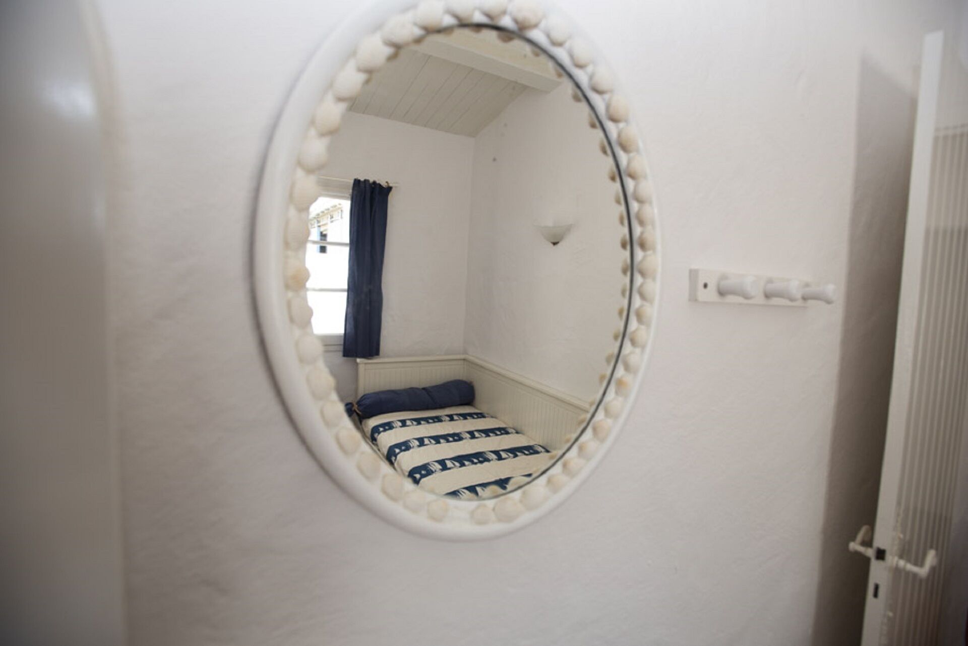 Une chambre avec un lit, un miroir et une fenêtre avec des rideaux.