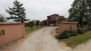 A gravel driveway leading to a house with a tiled roof and a small porch. - Small country house in the heart of the vineyards DU (Fronton)