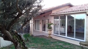 A house with a large patio, a stone wall, and a tree. - Small country house in the heart of the vineyards DU (Fronton)