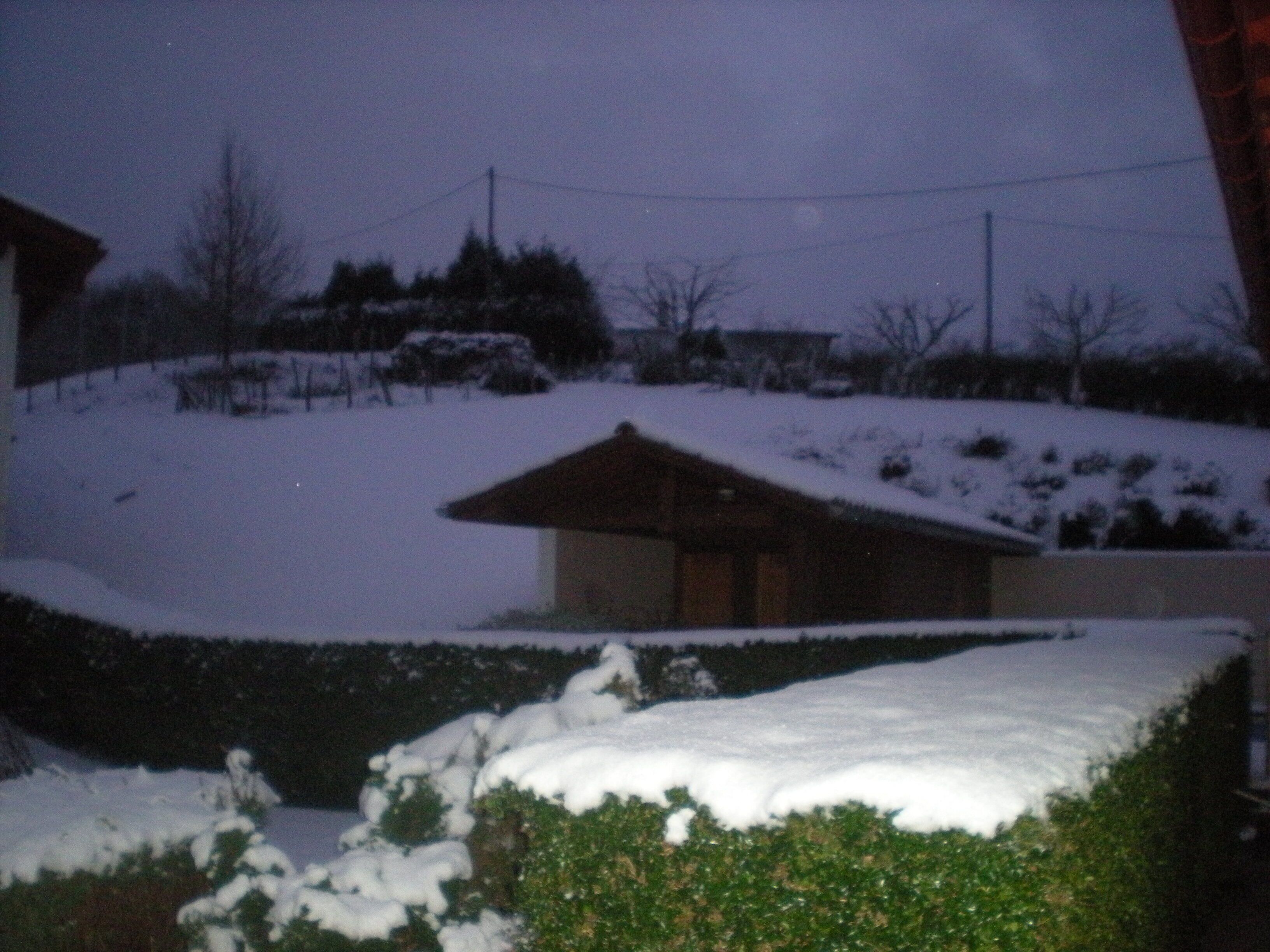 Un paysage enneigé avec une maison et une colline.