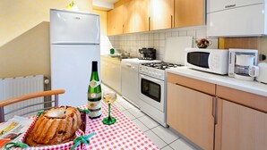 A kitchen with wooden cabinets, a refrigerator, a stove, and a microwave. - Terraced country house, 10 minutes from the slopes, at the foot of the mountains  (Breitenbach-Haut-Rhin)