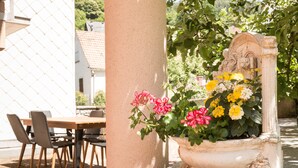 A white column with a flower pot containing pink and yellow flowers, a table with chairs, and a fence in the background. - Terraced country house, 10 minutes from the slopes, at the foot of the mountains  (Breitenbach-Haut-Rhin)