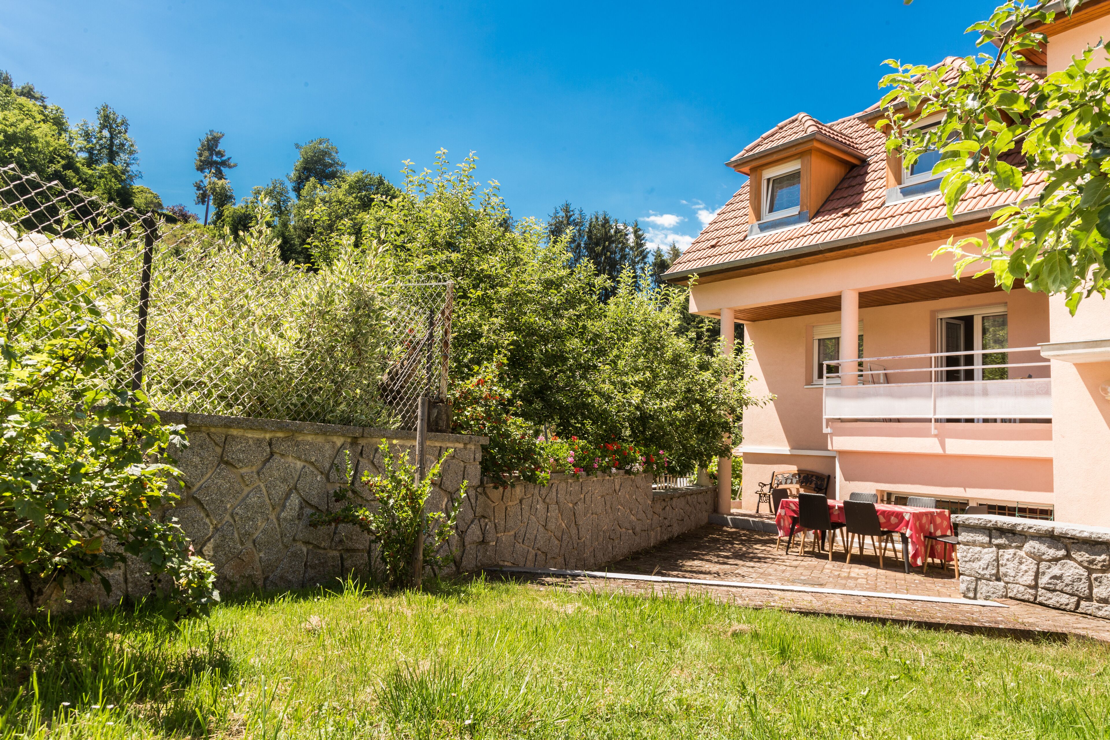 Une maison à deux étages avec un mur en pierre et un balcon.