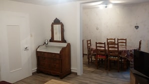 A room with a wooden dresser, a mirror, a dining table with chairs, and a television. - APARTMENT 1ST FLOOR 4 ROOMS 2 BEDROOMS 2-4PERS (Colmar)