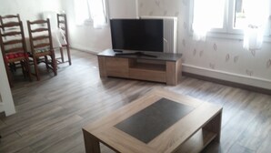 A living room with a wooden coffee table, a TV on a wooden stand, and two wooden chairs. - APARTMENT 1ST FLOOR 4 ROOMS 2 BEDROOMS 2-4PERS (Colmar)