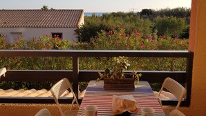 A table set for two with a striped tablecloth, two white chairs, a small potted plant, and a bag of snacks. - Studio cabin 4 pers, in quiet residence with swimming pool, 50 m from the beach (Saint-Cyprien)