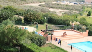 A pool area with a view of the sea, surrounded by greenery and a parking lot. - Studio cabin 4 pers, in quiet residence with swimming pool, 50 m from the beach (Saint-Cyprien)