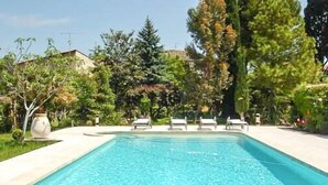 A rectangular swimming pool with clear blue water, surrounded by a concrete deck. There are lounge chairs along the edge of the pool. - Apartment in traditional farmhouse with swimming pool for 2 people, 2 bedrooms (Saint-Rémy-De-Provence)