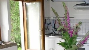 A wooden dining table with a metal pitcher and a vase of flowers. - Old Farmhouse (Rupt-Sur-Moselle)
