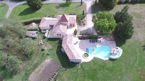Una casa grande con piscina, rodeada de un césped cuidado y un jardín.