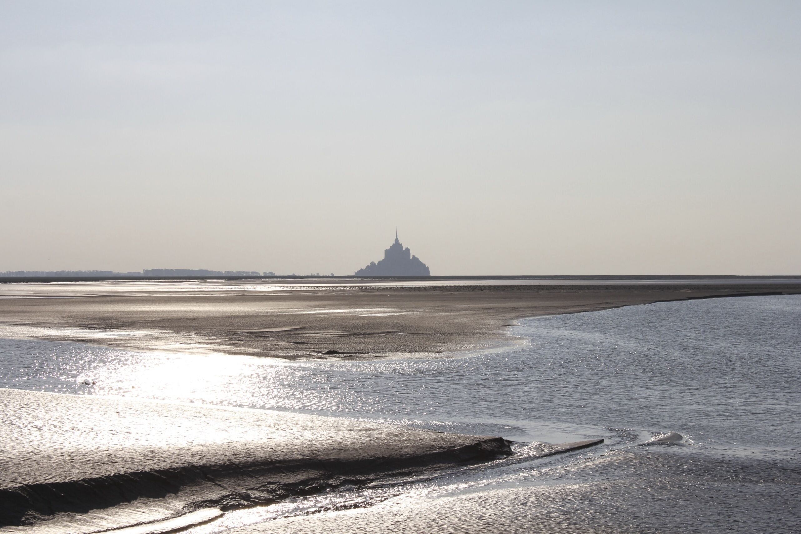 Une plage avec une île visible au loin.
