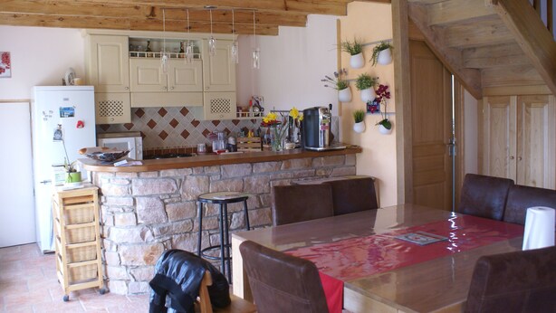 Een keuken met een stenen kookeiland, houten plafond en barstoelen.