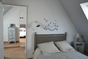 Een slaapkamer met een bed, nachtkastje, dressoir en een wanddecoratie.