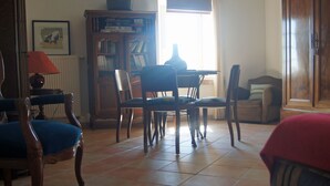 A dining area with a table, chairs, a bookshelf, and a radiator. - Large traditional stone house with swimming pool (Murs)