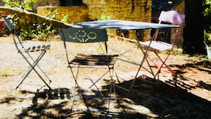 An outdoor seating area with a stone wall, a table, and two chairs. - Large traditional stone house with swimming pool (Murs)
