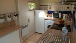 A compact kitchen with a washing machine, a refrigerator, a toaster, and a sink. - Warm house in the heart of a forest, close to shopping and beaches (Fouesnant)
