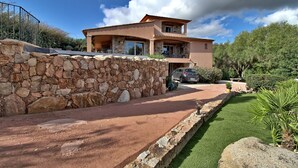 Una casa a due piani con un muro in pietra e un vialetto lastricato che conduce all'ingresso.
