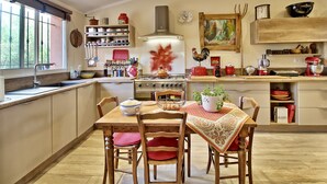 Una cucina con tavolo e sedie, un fornello e diversi oggetti da cucina.