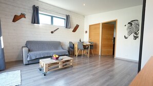 A modern living room with a grey sofa, wooden coffee table, and a dining area with chairs and a table. - Cottage by the sea and close to the town center in Cabourg. (Cabourg)