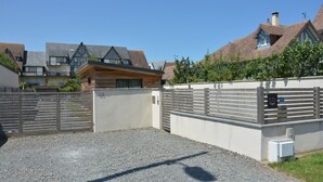 A gated residential area with a gravel driveway, a wooden fence, and houses with distinct architectural styles. - Cottage by the sea and close to the town center in Cabourg. (Cabourg)