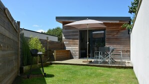 A modern outdoor patio with a wooden deck, a table and chairs, and a large umbrella. - Cottage by the sea and close to the town center in Cabourg. (Cabourg)