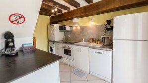A compact kitchen with a washing machine, microwave, oven, and refrigerator.