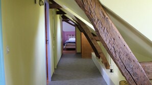 A narrow hallway with a sloped ceiling and exposed wooden beams.