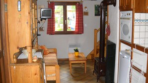 Una cucina compatta con un fornello, un tavolino e una televisione.