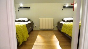 Una habitación con dos camas, un radiador y suelo de madera.
