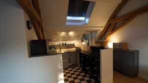 Una cocina con piso a cuadros, vigas de madera, tragaluz y estufa moderna.