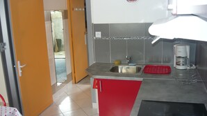 Una cocina con un lavamanos, una cafetera y una encimera roja.