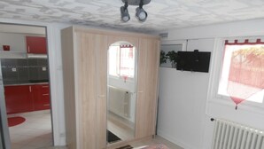 Un dormitorio con cama, armario, radiador y ventana con cortinas.