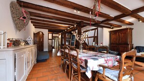 A dining area with a wooden table, chairs, and a white cabinet. - Manala ***, Alsatian house for 7 to 9 people in Kaysersberg - 3 bedrooms, 2 bathrooms, veranda (Kaysersberg-Vignoble)