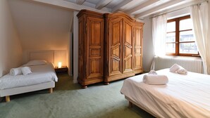 A bedroom with two single beds, a wooden wardrobe, a radiator, and a window with curtains. - Manala ***, Alsatian house for 7 to 9 people in Kaysersberg - 3 bedrooms, 2 bathrooms, veranda (Kaysersberg-Vignoble)