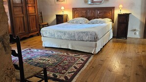 A bedroom with a wooden bed, a small window, a chair, and a rug.