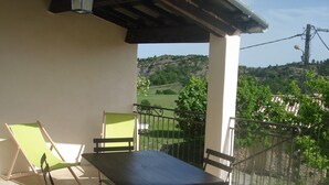 Un patio con una mesa y sillas, una silla verde y vista a una colina.