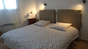 Un dormitorio con cama, dos lámparas de noche, una mesita de noche y una ventana con cortinas.